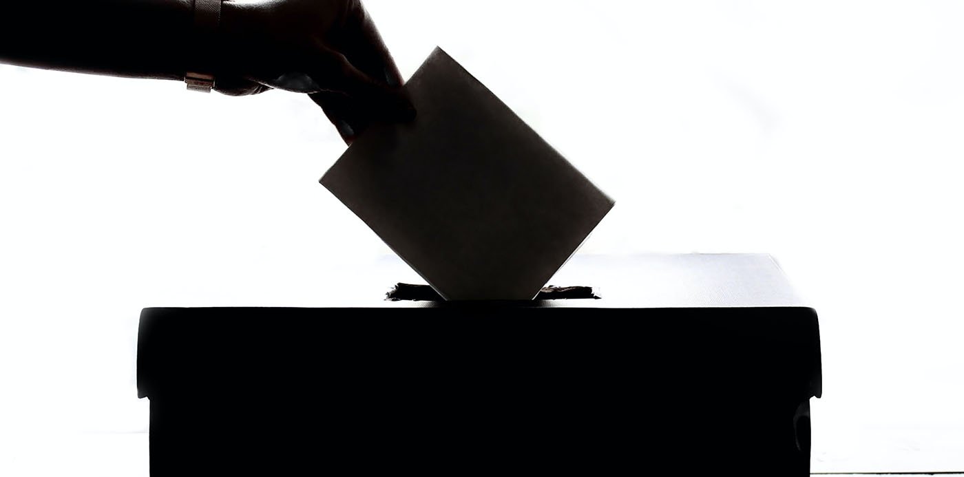Una persona introduciendo un voto en una urna