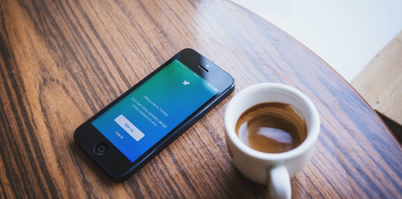 Una tassa de cafè i un mòbil amb la pàgina d'accés a Twitter a la pantalla