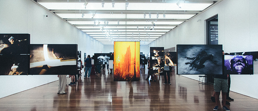 An art installation in a large room with photographs hanging from cables
