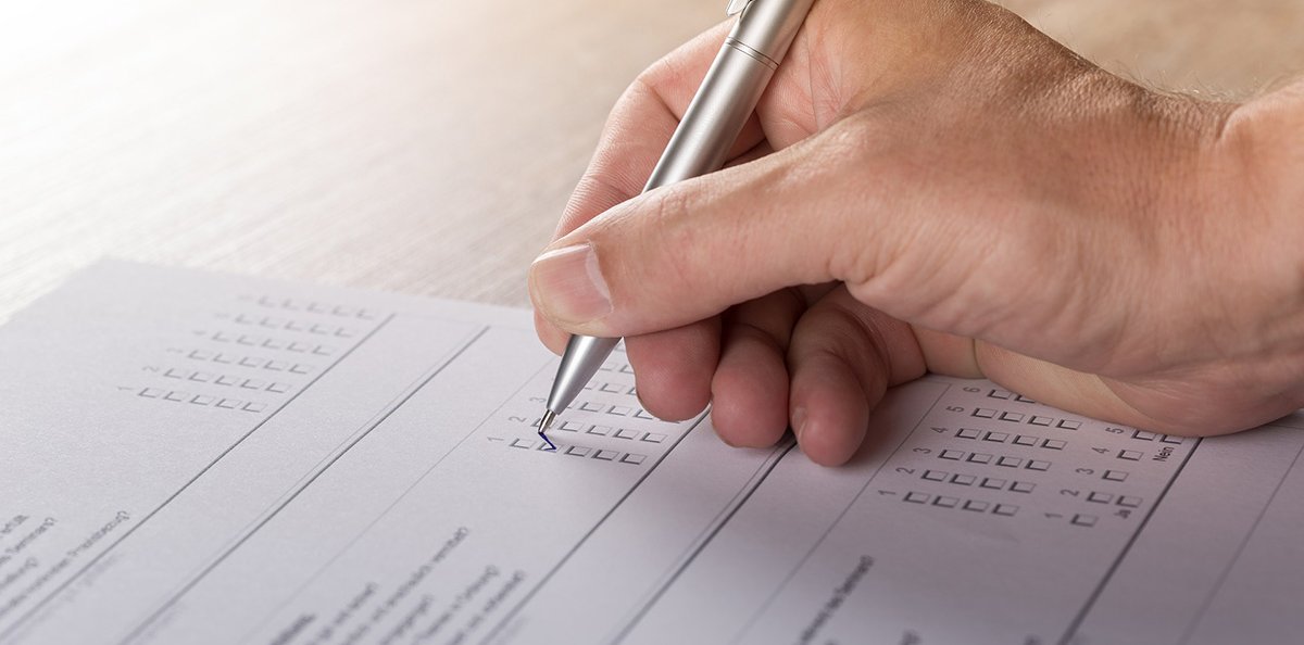 A person filling out a survey on a sheet of paper