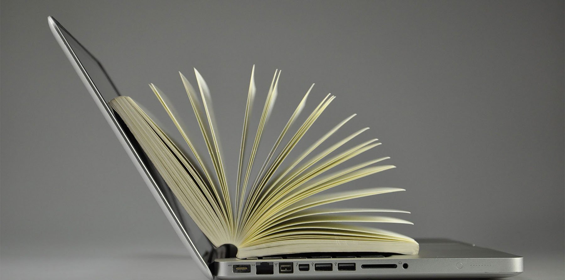 An open laptop with an open book on top