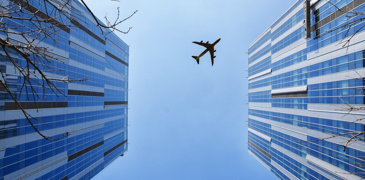 Avión en el cielo entre dos edificios