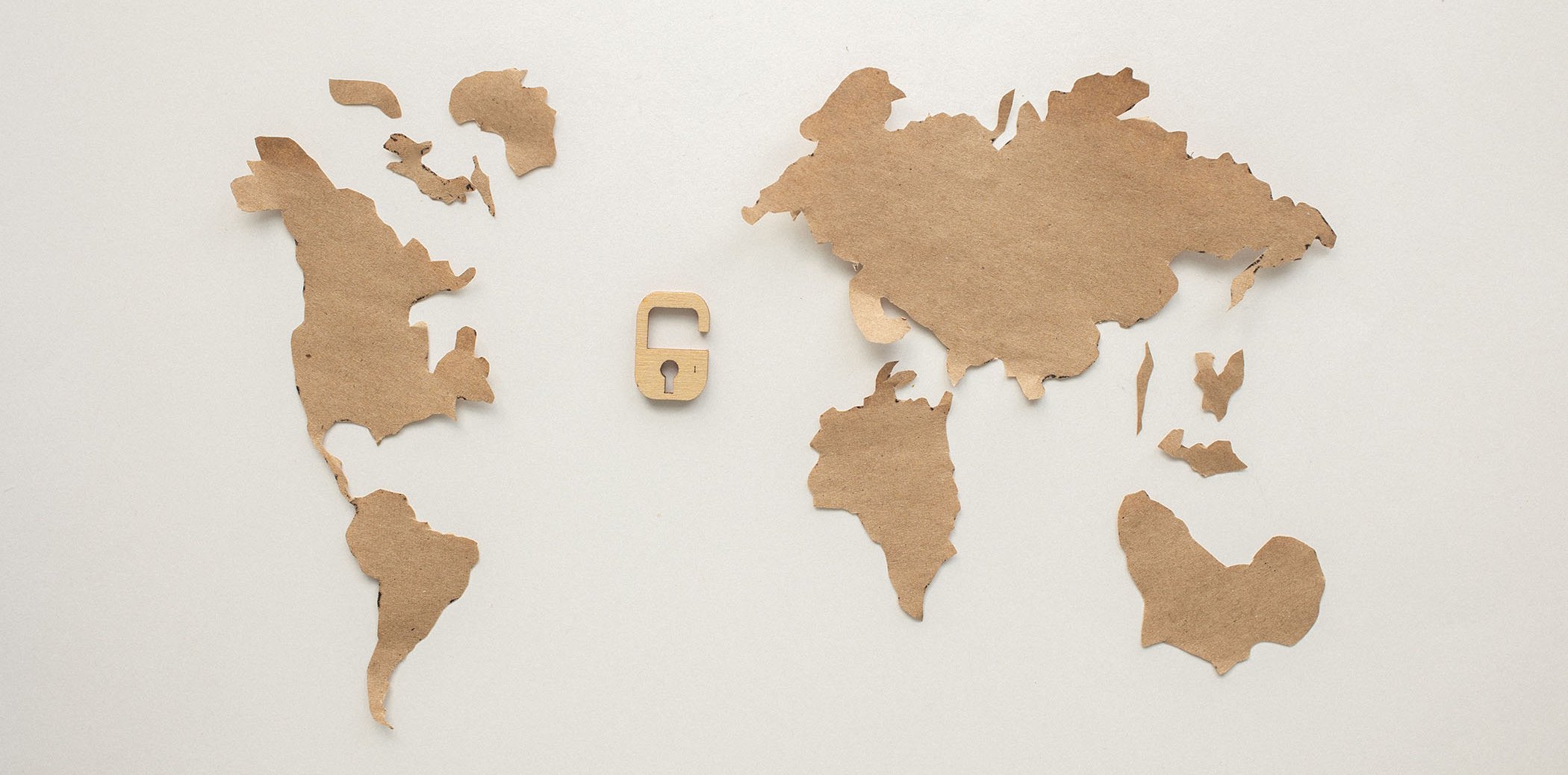 A world map with an open padlock in the middle, both made of cardboard