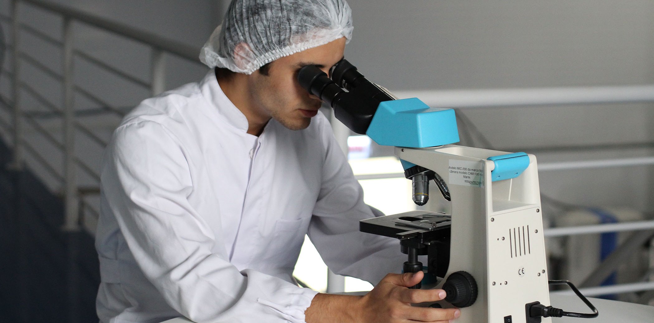 Un científic utilitzant un microscopi amb una revista al costat