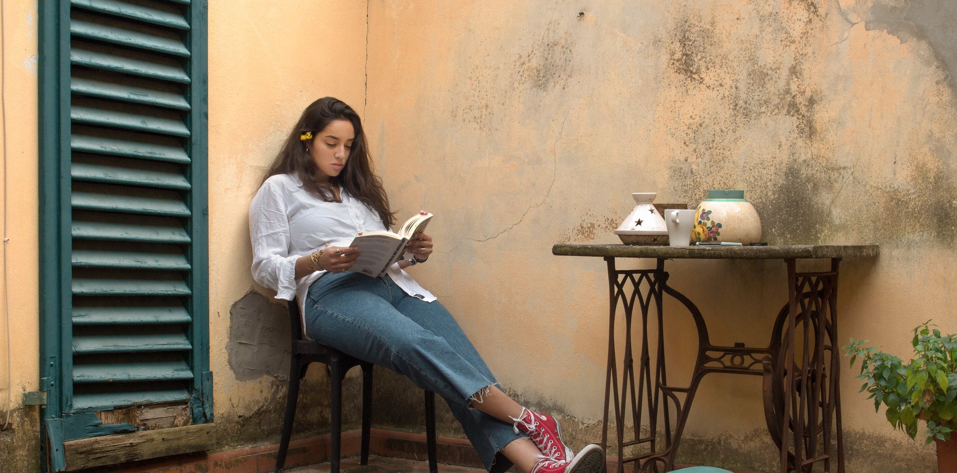 A girl is reading sitting at a terrace