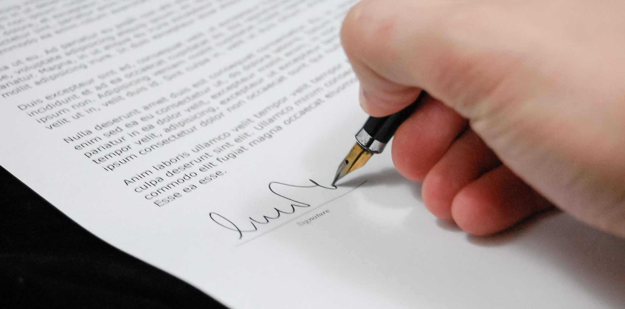 A person signing a document with a fountain pen