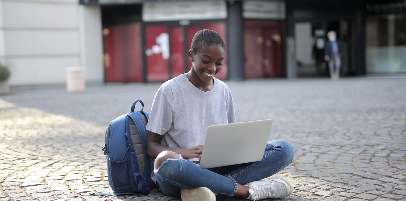 A girl sitting on the floor using a laptop