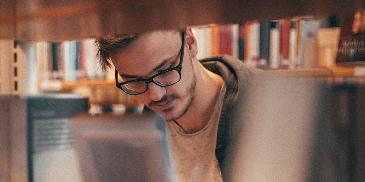 Una persona mirant les prestatgeries d'una biblioteca Una persona mirant les prestatgeries d'una biblioteca