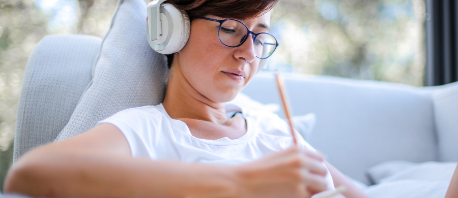 A girl looking at the computer with headphones