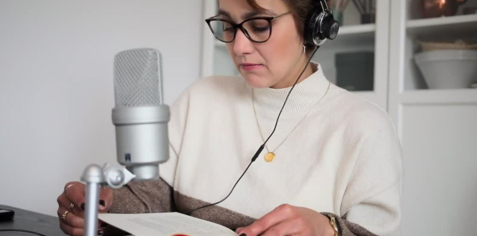  A woman reading a text with a microphone and headphones