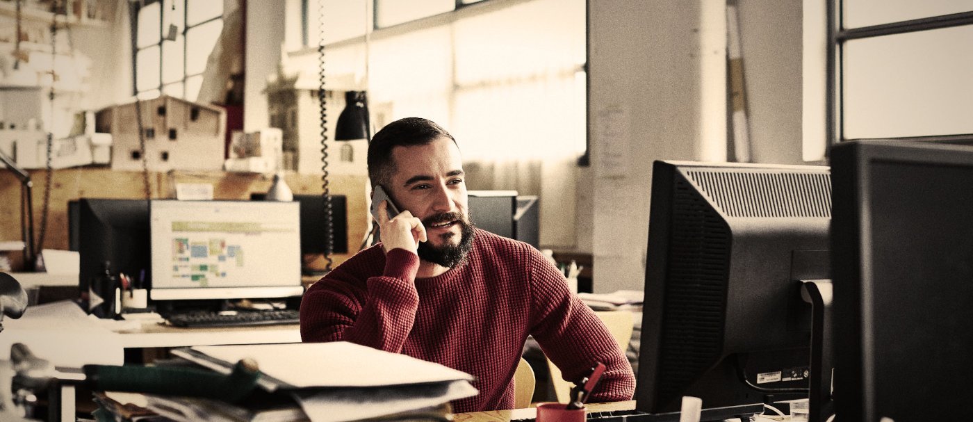 One man talking on the phone in front of a computer