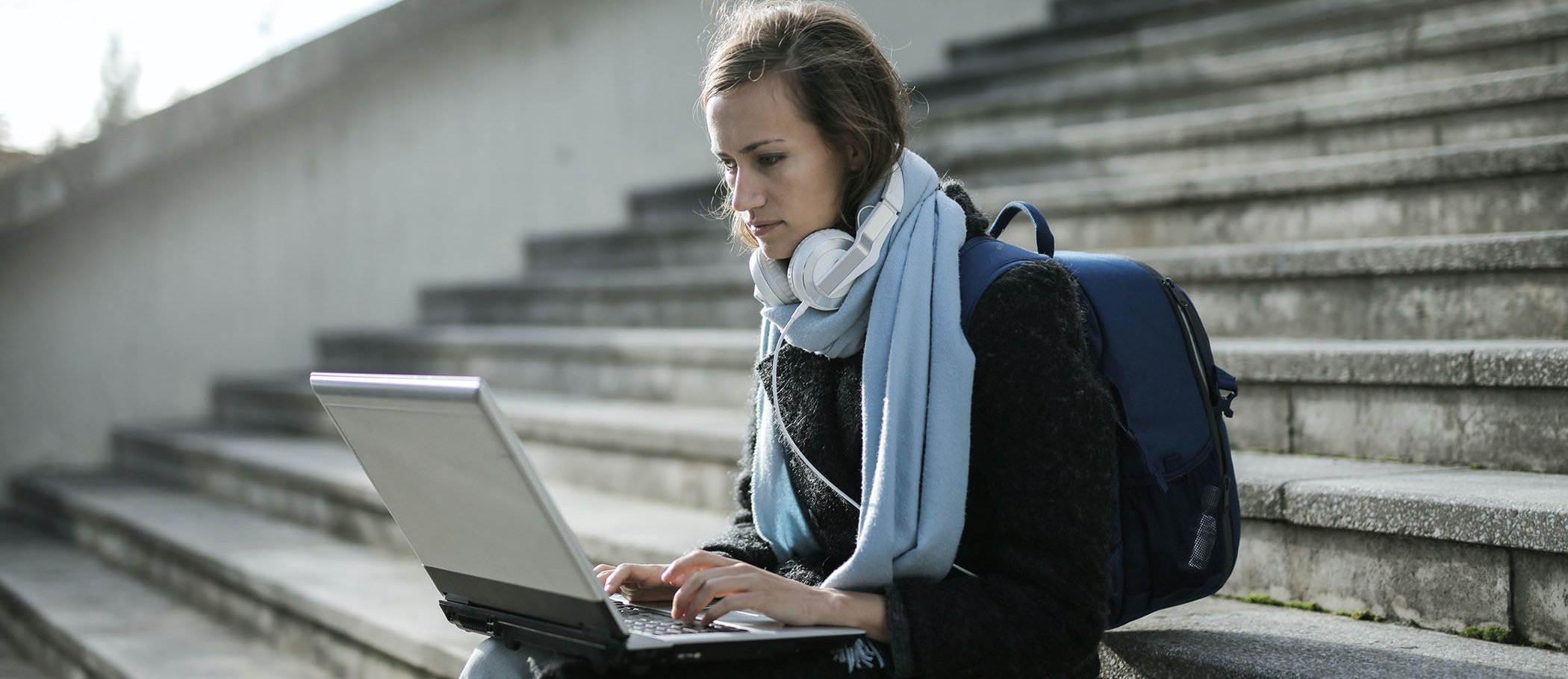 A woman sitting on a stairwell with an open laptop