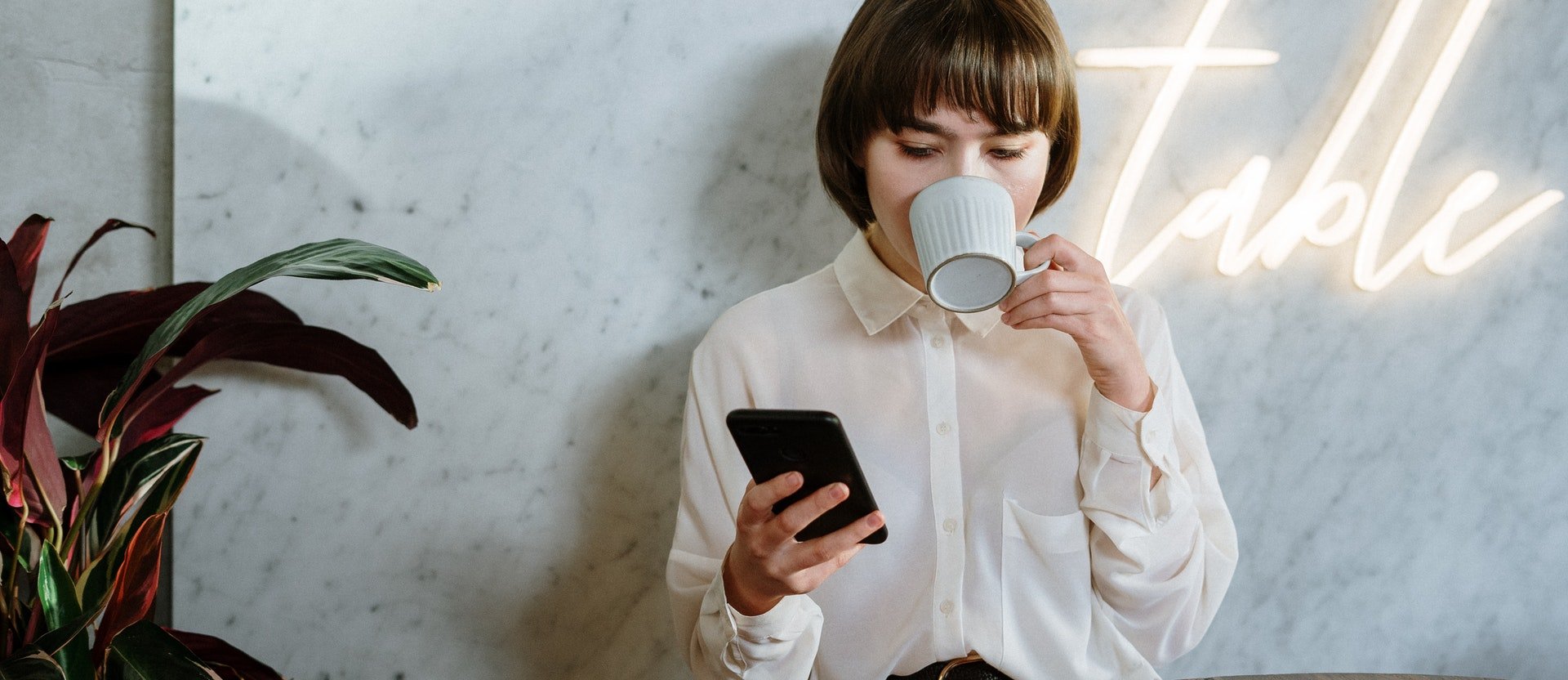 Mujer tomando un café mientras consulta el móvil