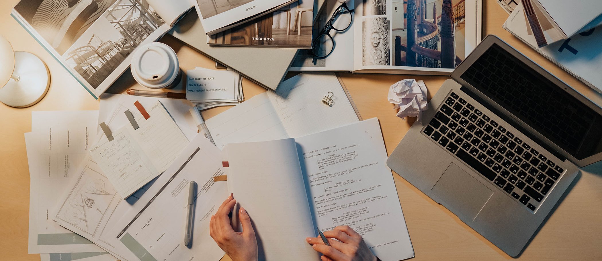 Una mesa con folios de papel, libros y un portátil