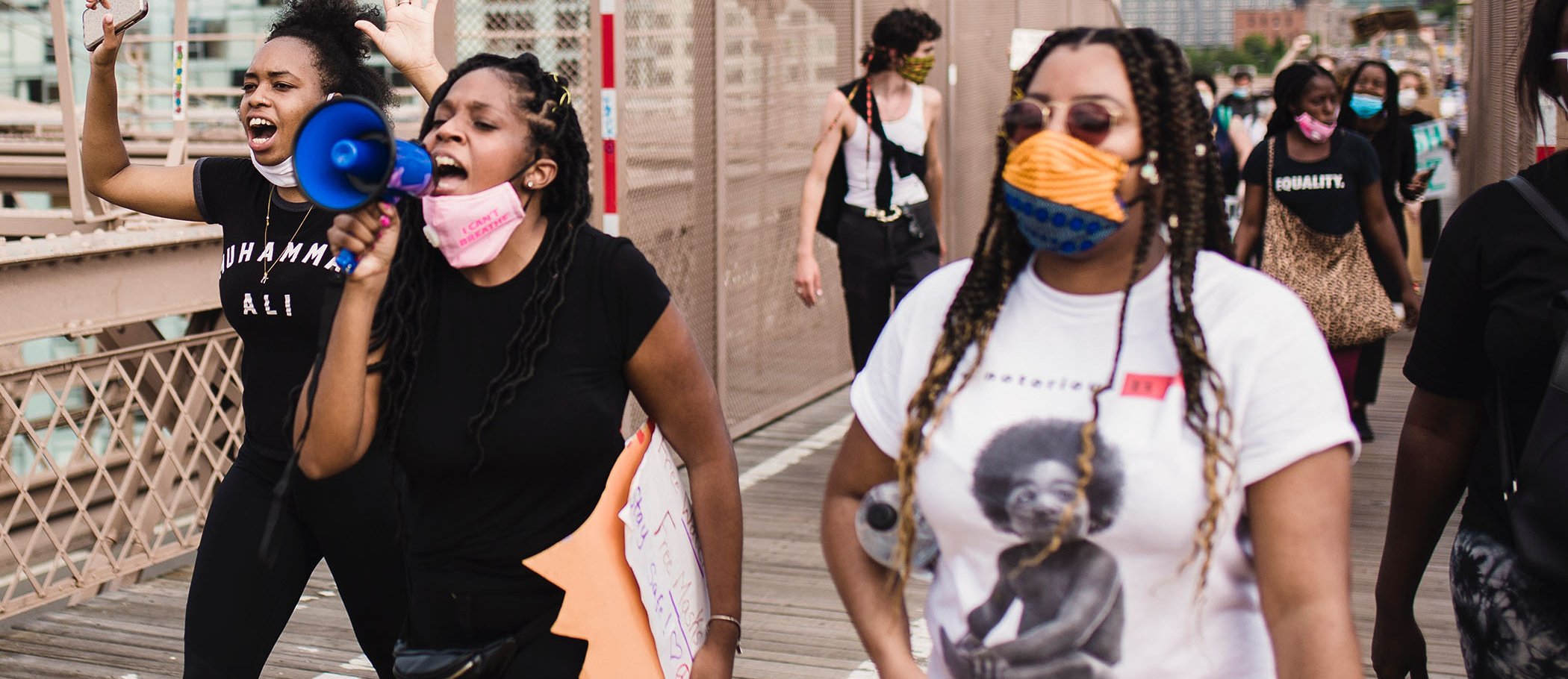 Three young women, one of them with a megaphone, participating in a demonstration