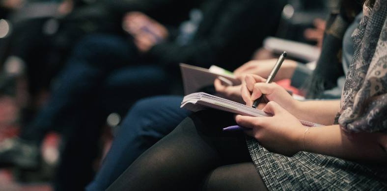 People at a conference taking notes in a notebook