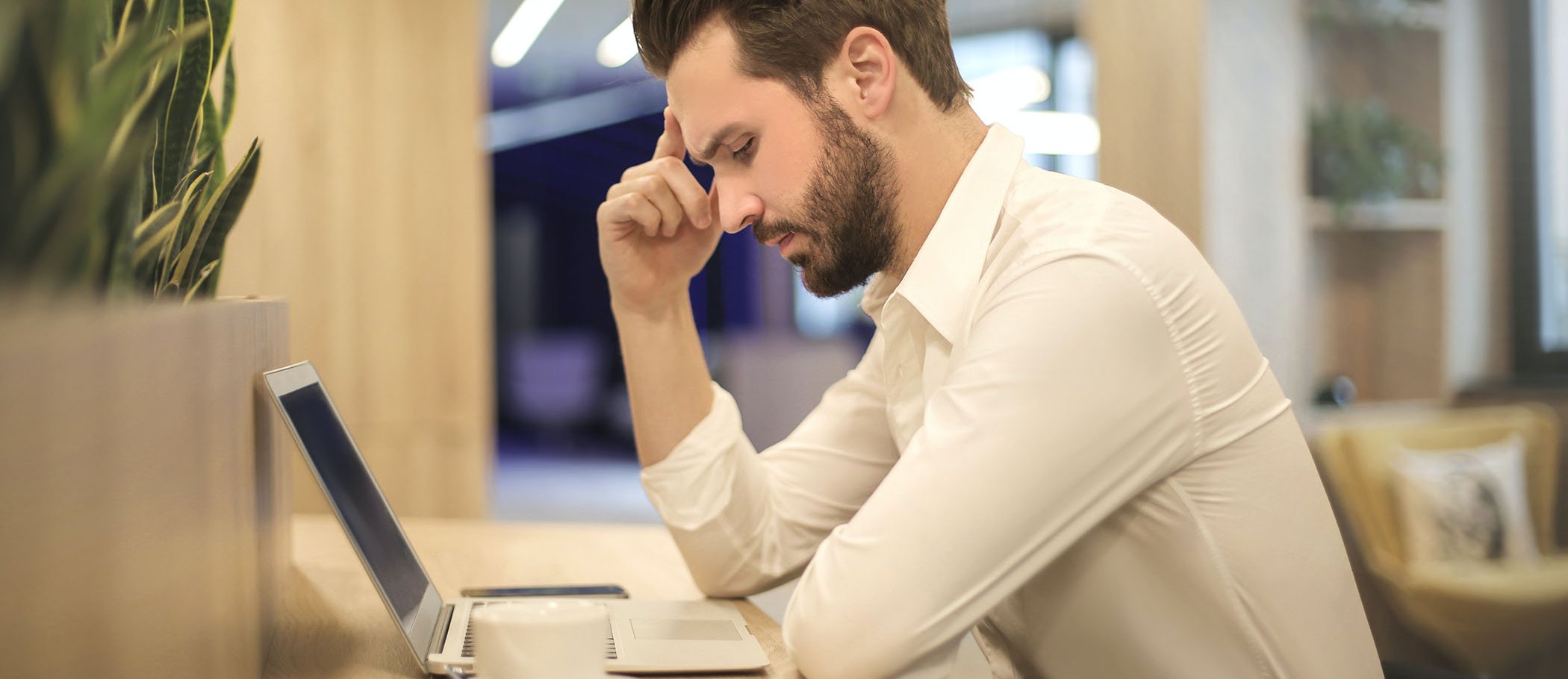 A man with a thoughtful expression looking at a laptop screen