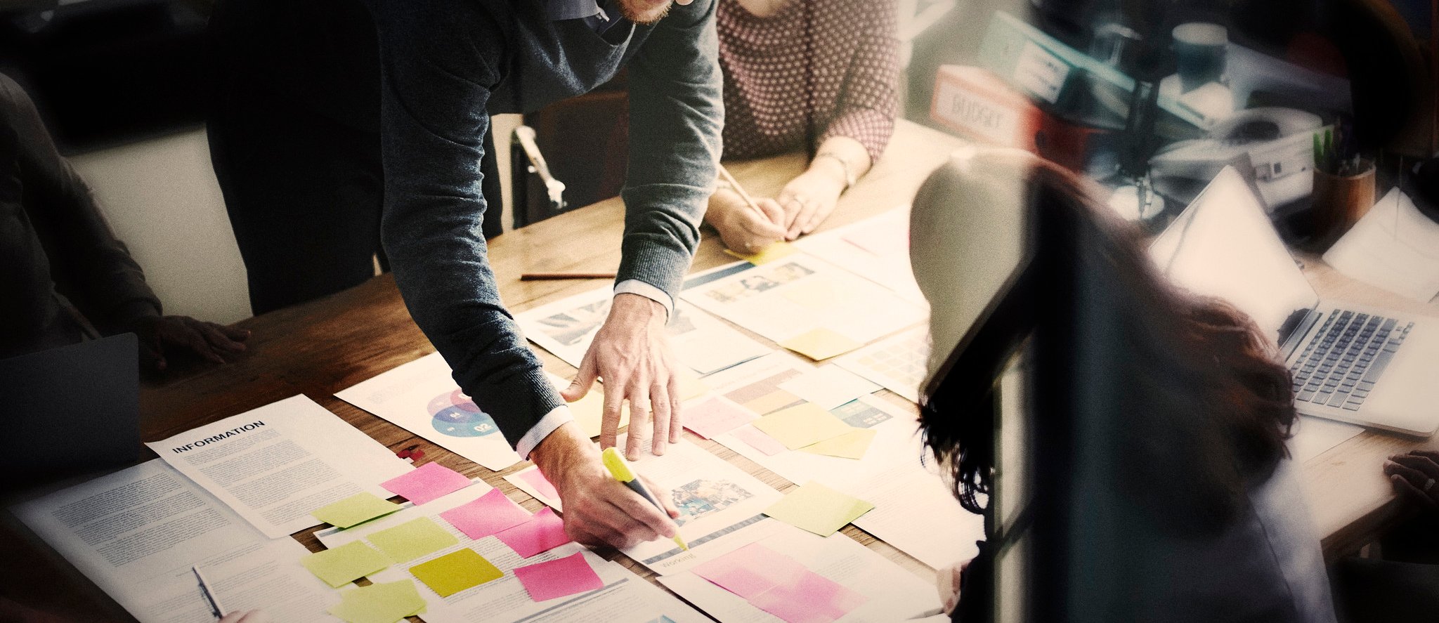 A group of people working around a table with paper sheets and post-its