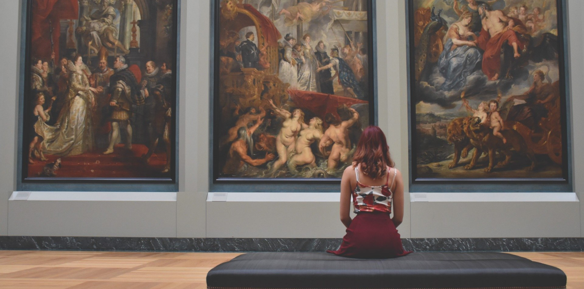 A woman in front of three paintings