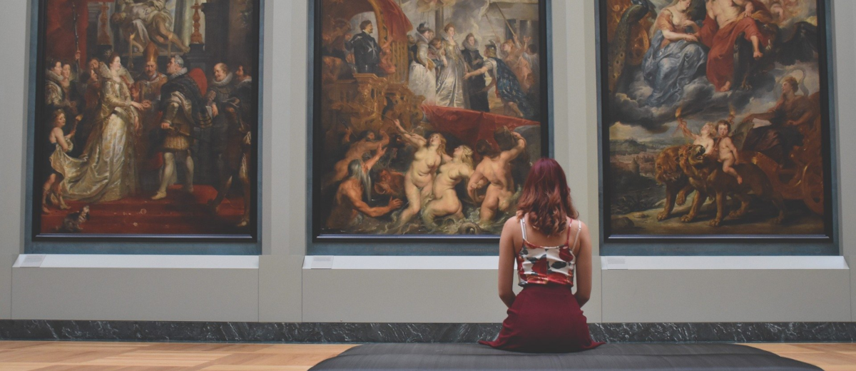 A woman in front of three paintings