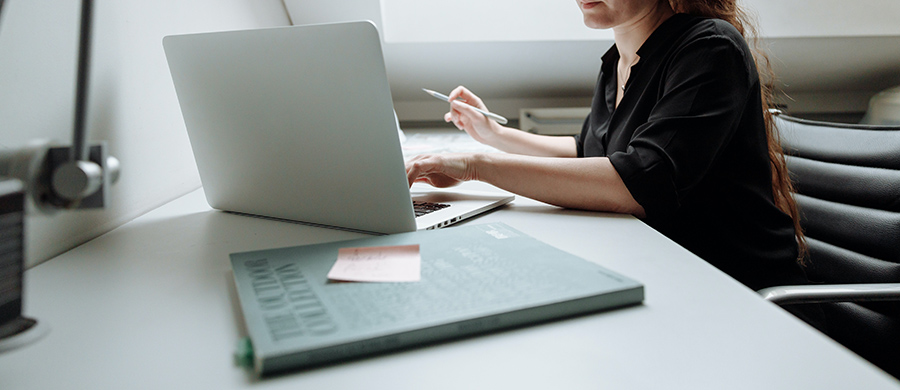 A magazine in the foreground and a woman with a laptop in the background