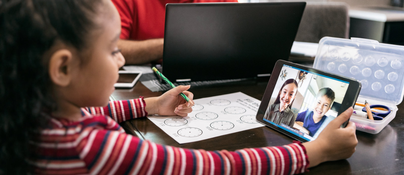 Educación en línea: niña mirando una tablet y hablando con los compañeros de clase