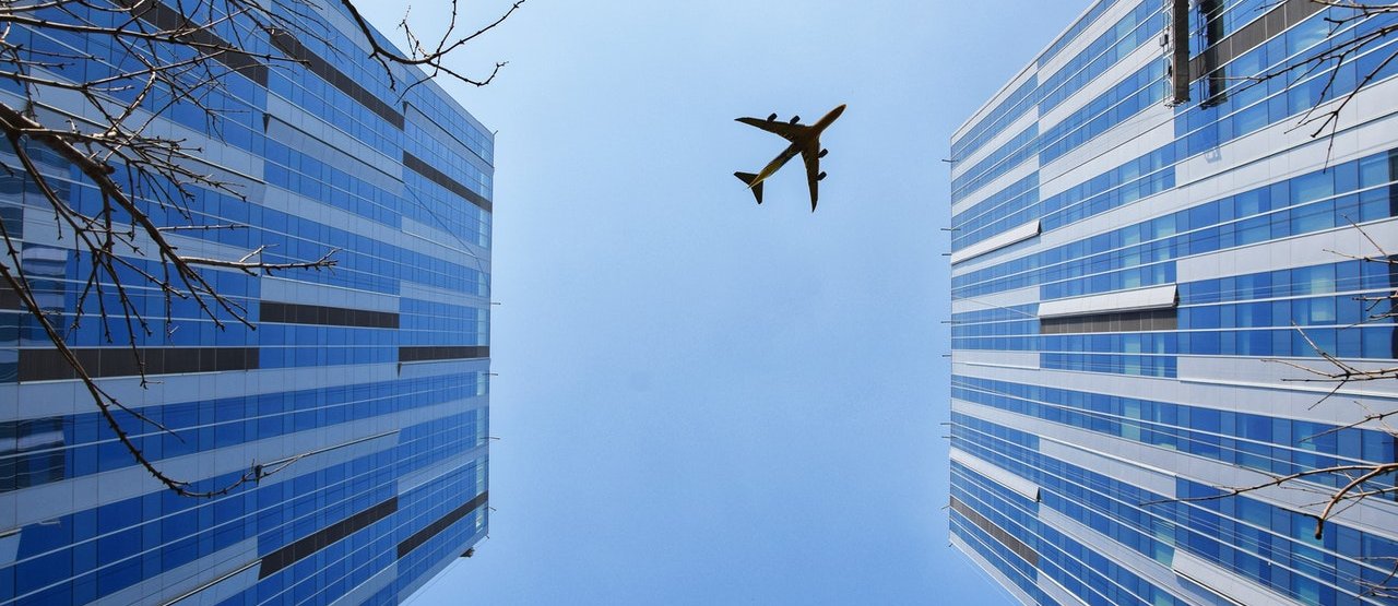 Avión en el cielo entre dos edificios