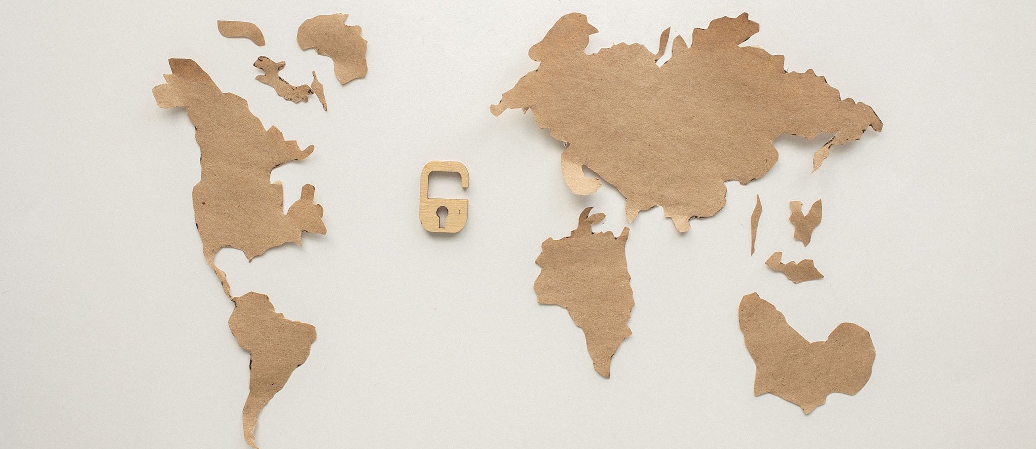 A world map with an open padlock in the middle, both made of cardboard