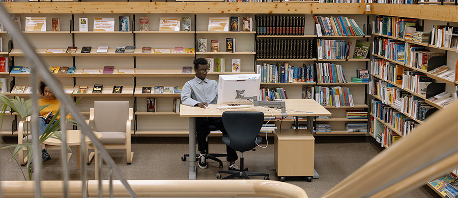 A person using a computer in the middle of a library