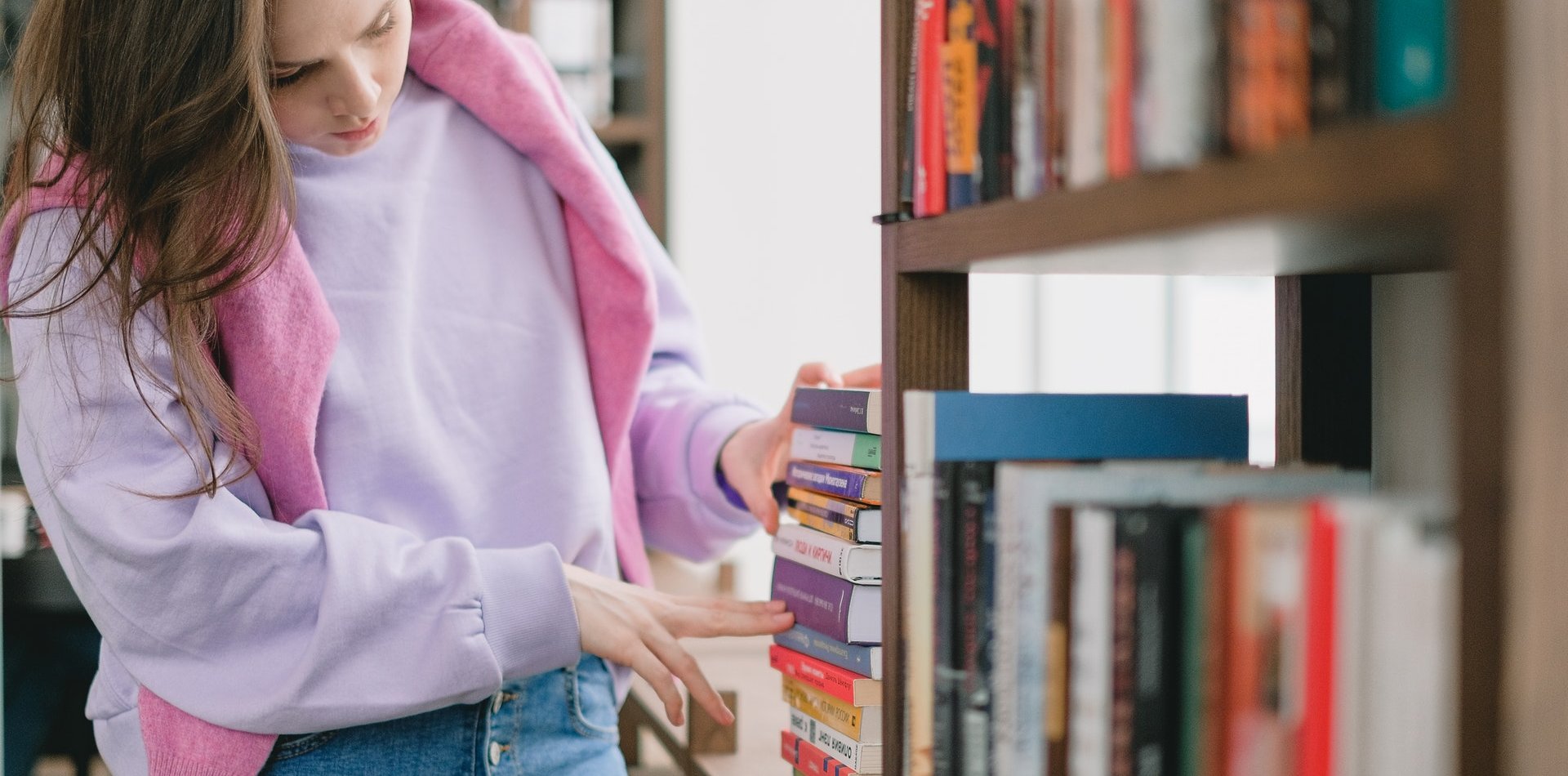 Noia col·locant llibres a una biblioteca