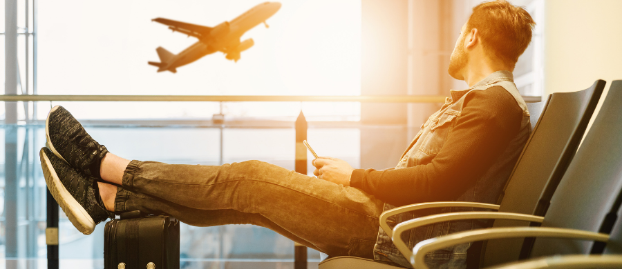 Un chico mirando un avión mientras mira el móvil 