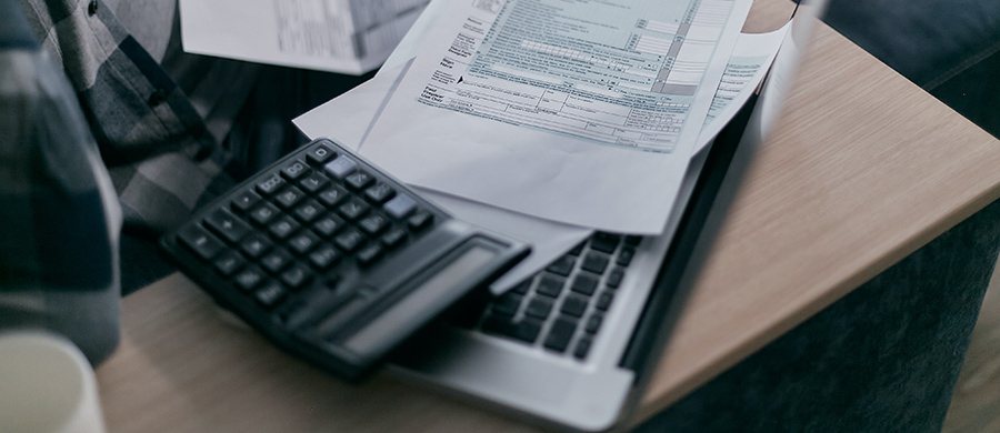 Una calculadora, un portàtil i un formulari de declaració d'impostos a sobre d'una taula