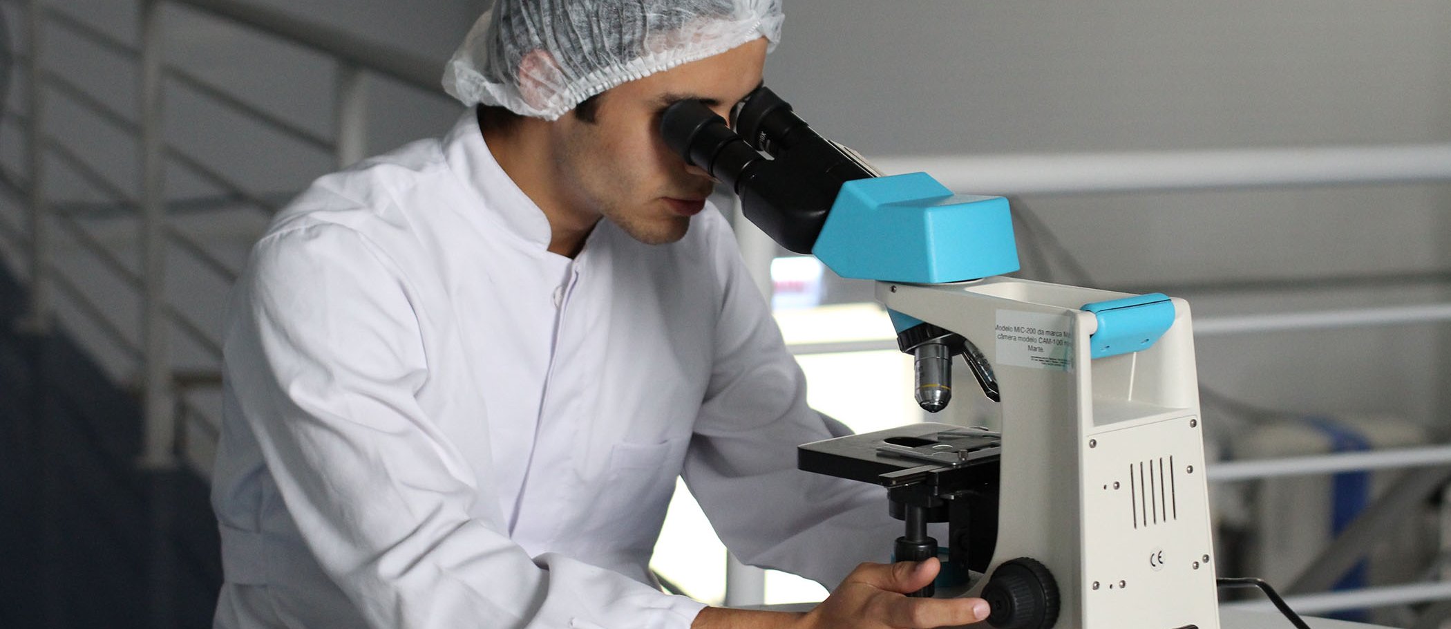 Un científic utilitzant un microscopi amb una revista al costat