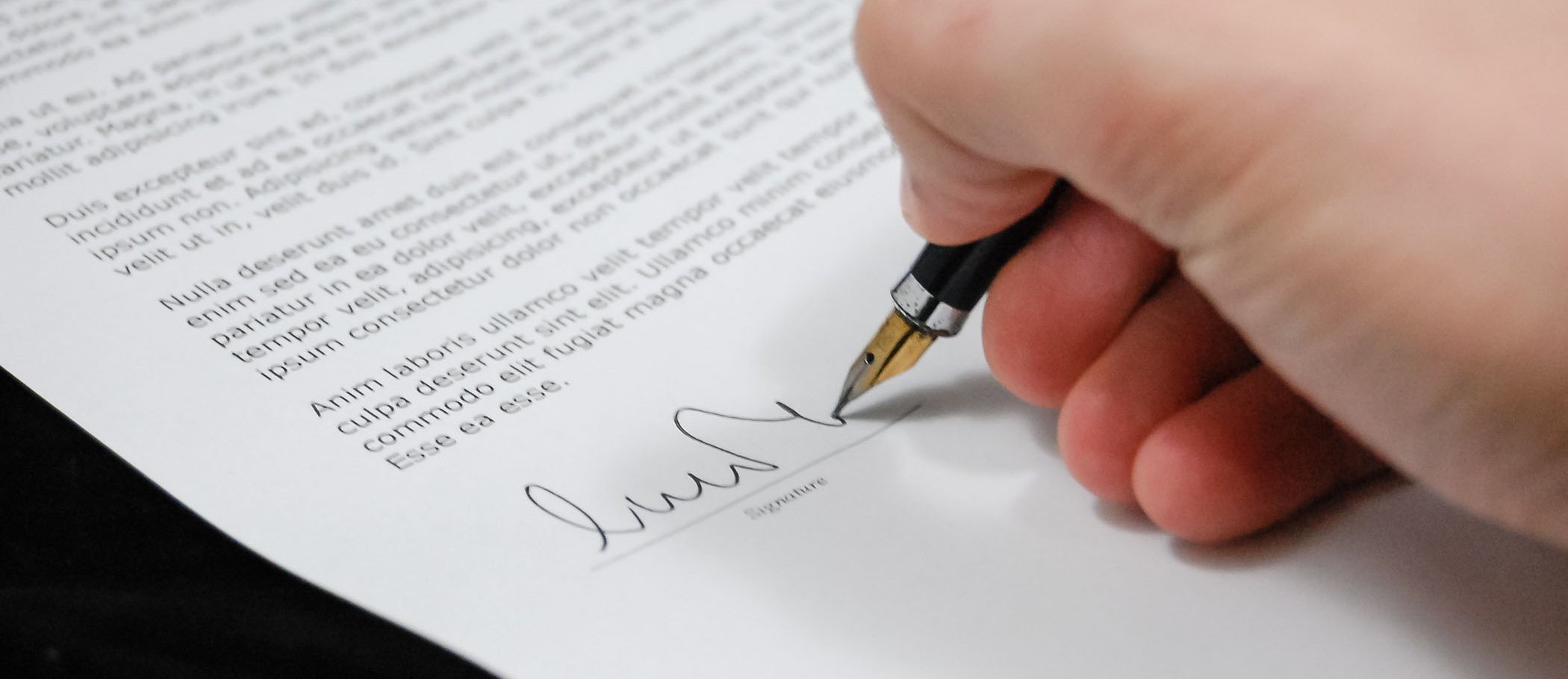 A person signing a document with a fountain pen