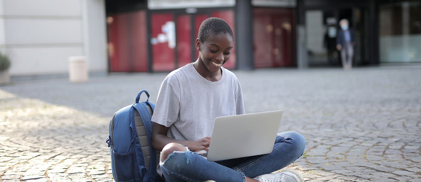 A girl sitting on the floor using a laptop