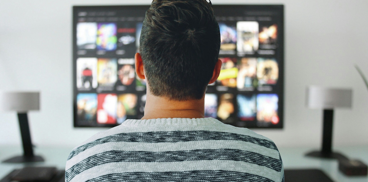 Un home mirant una televisió amb caràtules de pel·lícules