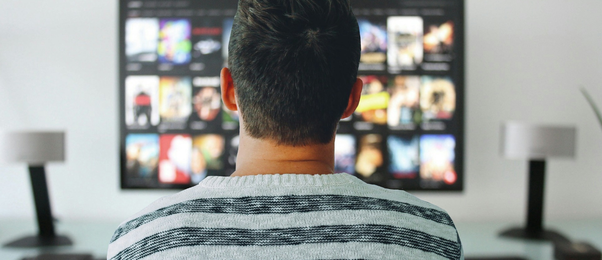 A man looking at a TV with movie covers