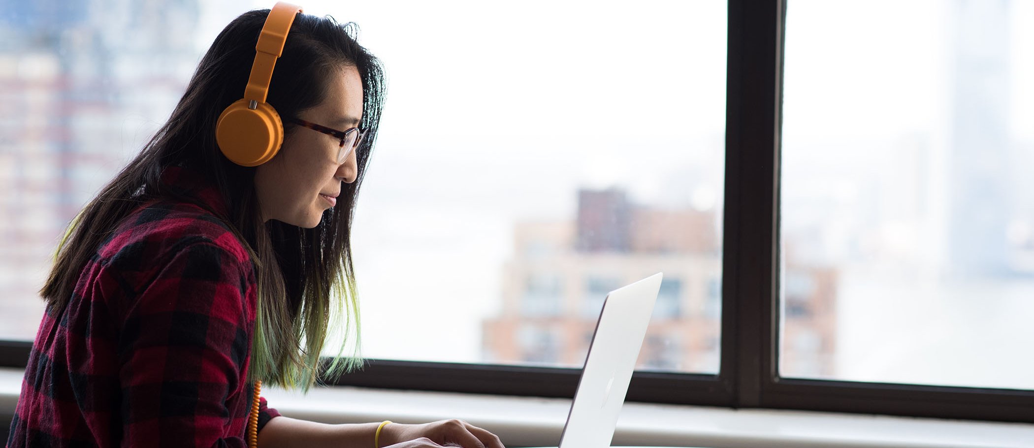 A woman with a laptop and a pair of headphones