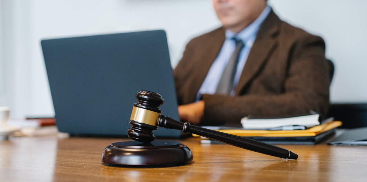 A man with a laptop and a gavel on the table