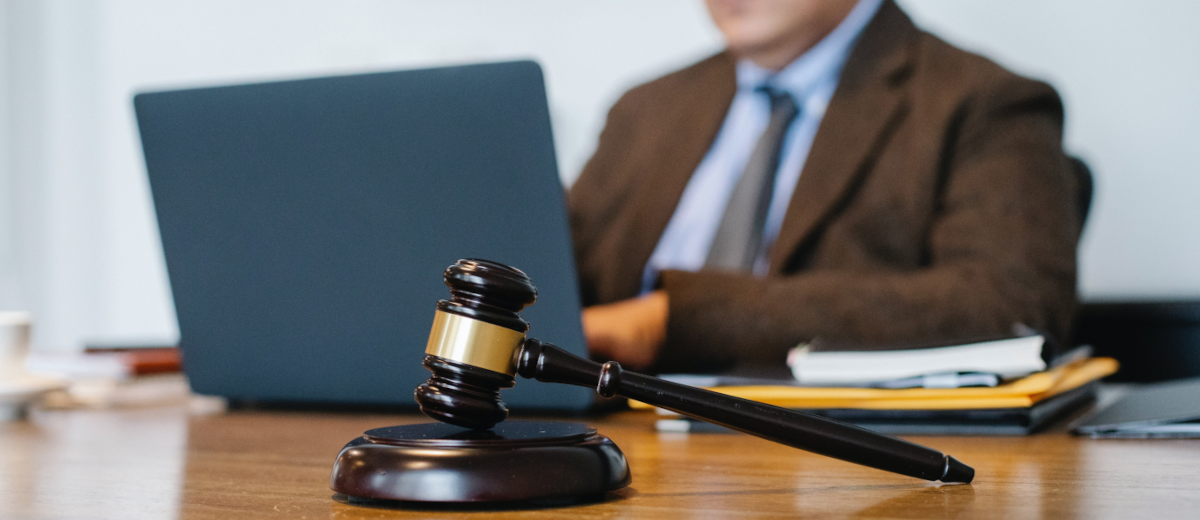 A man with a laptop and a gavel on the table