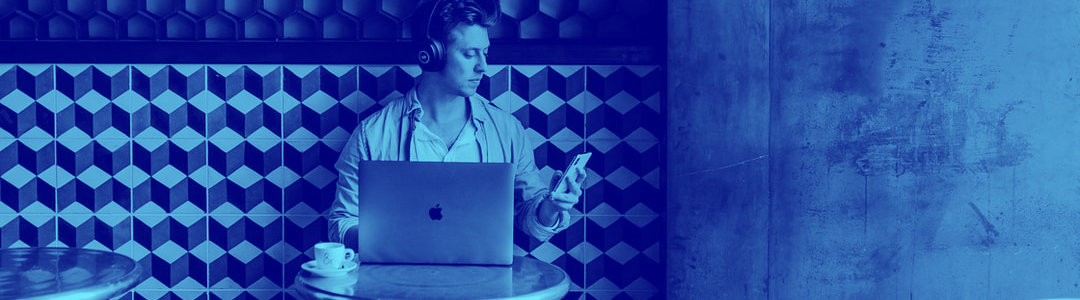 A young man with a laptop, a smartphone and a pair of headphones