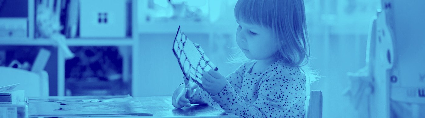 Una nena petita jugant amb unes tisores i un paper amb formes geomètriques