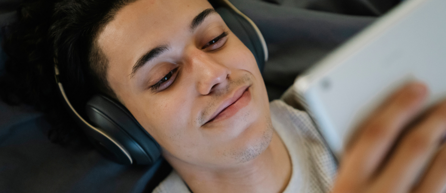 Un chico mirando una tableta con los auriculares