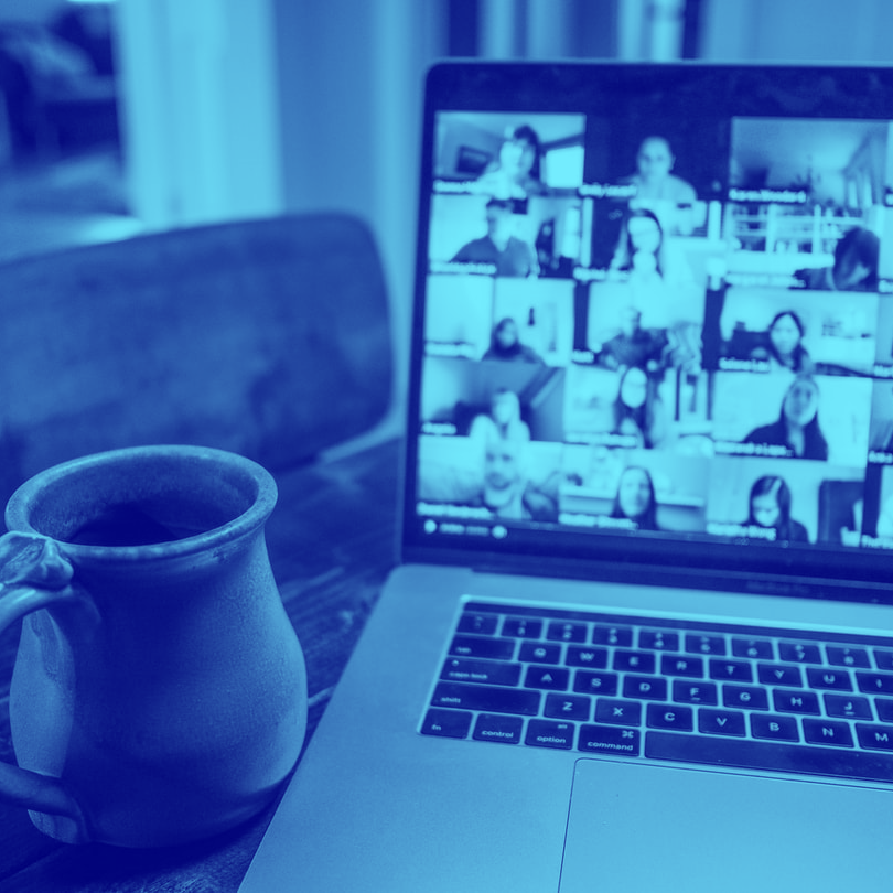 Ordenador en el que se hace videoconferencia con un taza en primer plano