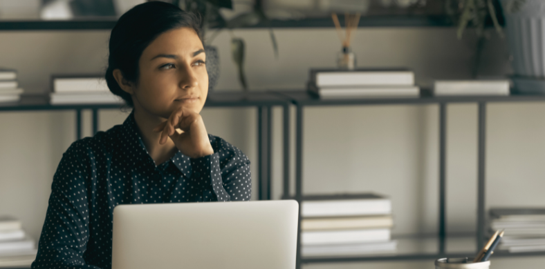 A woman with a thoughtful attitude while sitting in front of a computer.