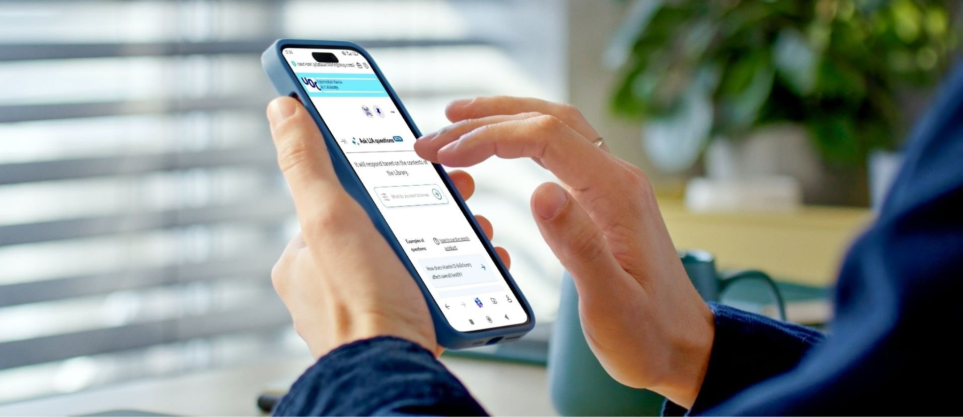 A la imatge es veu una persona sostenint un telèfon mòbil amb una mà mentre amb l’altra interactua amb la pantalla tàctil. El dispositiu mostra una pàgina web amb l'assistent de cerca. A la imatge es veu una persona sostenint un telèfon mòbil amb una mà mentre amb l’altra interactua amb la pantalla tàctil. El dispositiu mostra una pàgina web amb l'assistent de cerca.