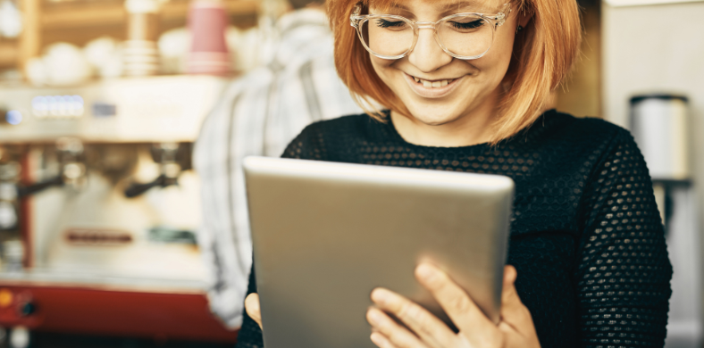 A girl looking at a tablet in a cafe