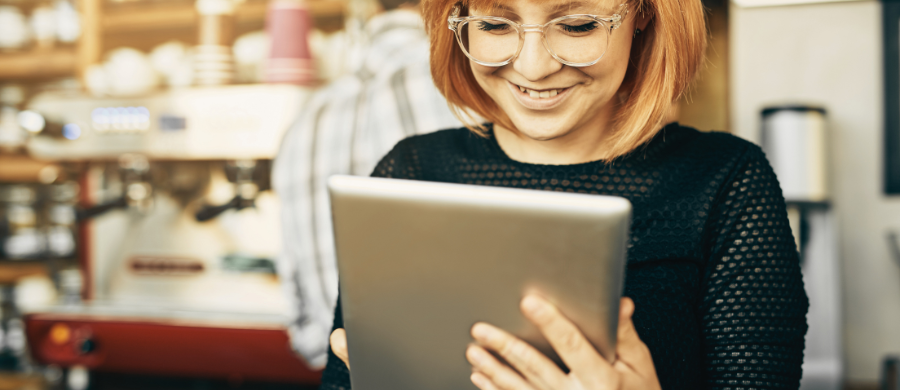 Una mujer mirando una tableta en una cafetería