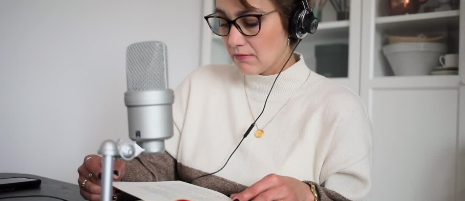  A woman reading a text with a microphone and headphones