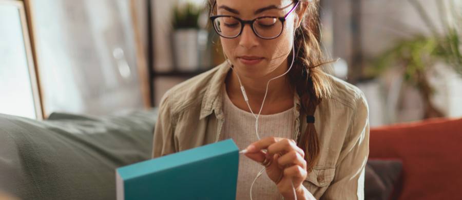 Una chica enchufando unos auriculares en un libro